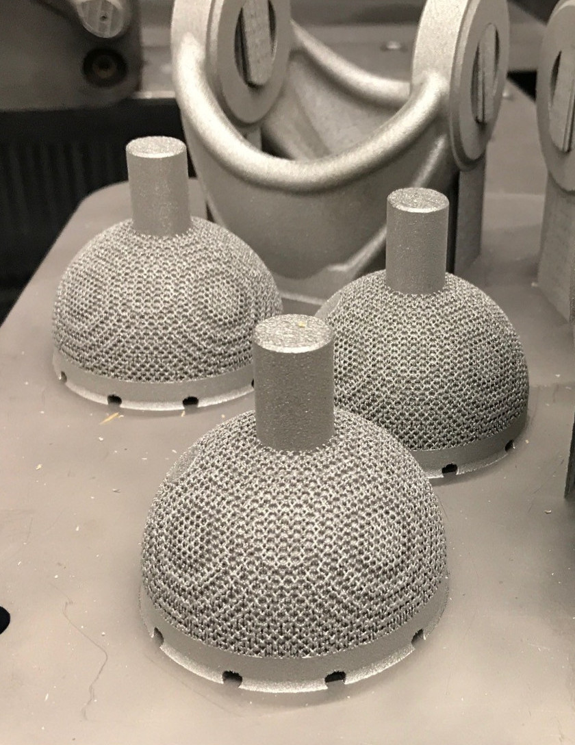 Hip cups on a build plate with cavities for powder removal